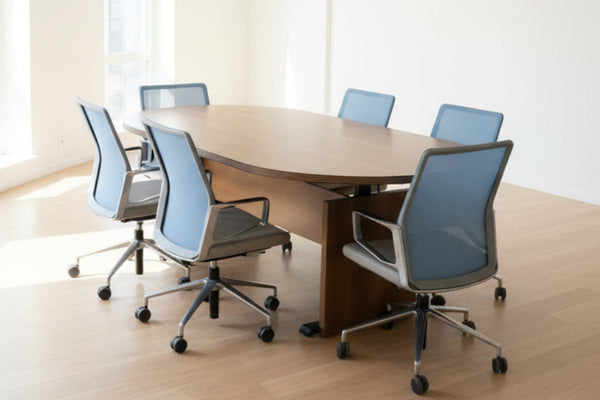 Round wooden table with blue chairs in a room with office furniture and signs.