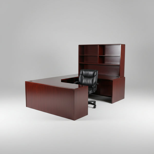 A dark reddish-brown wooden L-shaped desk with a matching hutch shelf unit, shown in a furniture showroom with other office furniture in the background.